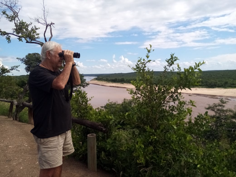 Allen overlooking river through binoculars